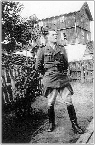 An SS man on the staff of the Belzec camp, posing in front of the flour mill used as an assembly place for Jews deported to the camp.
